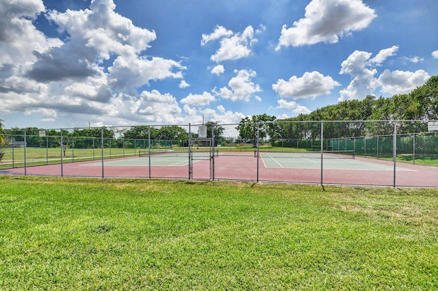 view of tennis court featuring fence and a yard