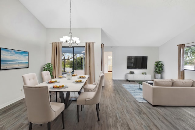 dining area featuring wood finished floors, vaulted ceiling, baseboards, and an inviting chandelier