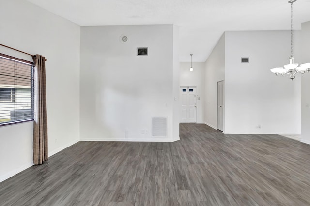 spare room with wood finished floors, visible vents, and a notable chandelier