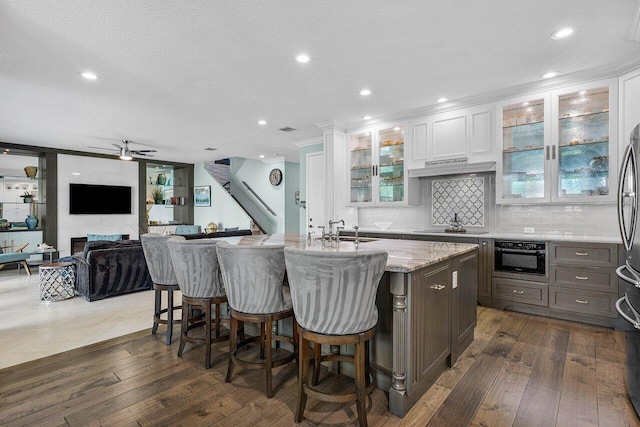 kitchen featuring dark wood finished floors, white cabinets, a sink, light stone countertops, and a kitchen bar