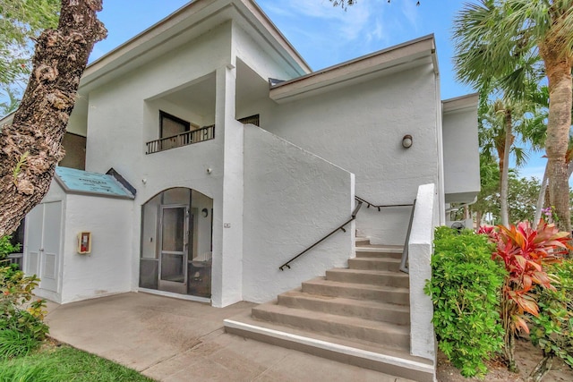 back of house featuring stairs, a balcony, and stucco siding