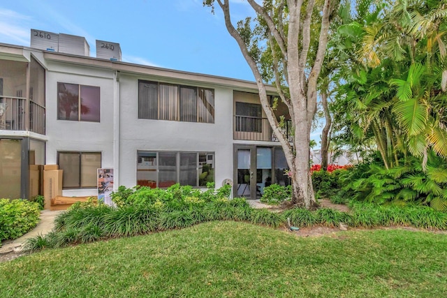 back of property featuring stucco siding and a lawn