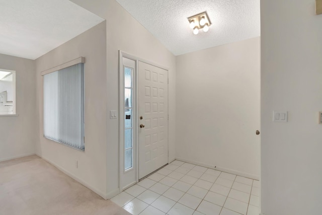 foyer featuring baseboards, a textured ceiling, lofted ceiling, and light tile patterned flooring