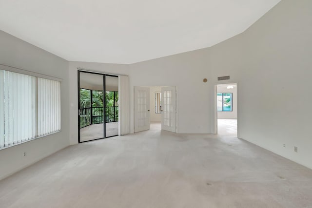 spare room featuring light colored carpet, visible vents, and a towering ceiling