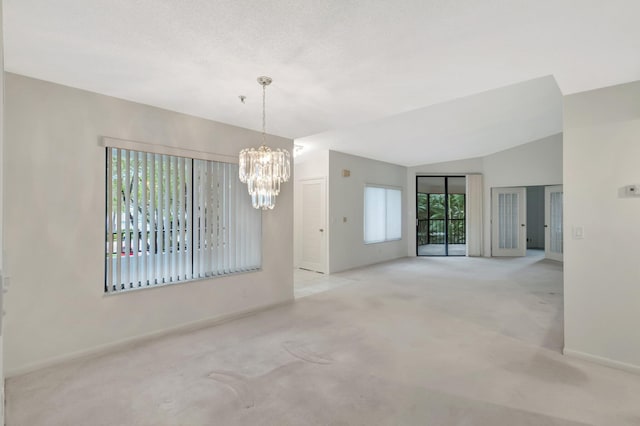 spare room with a notable chandelier, lofted ceiling, a textured ceiling, carpet floors, and baseboards