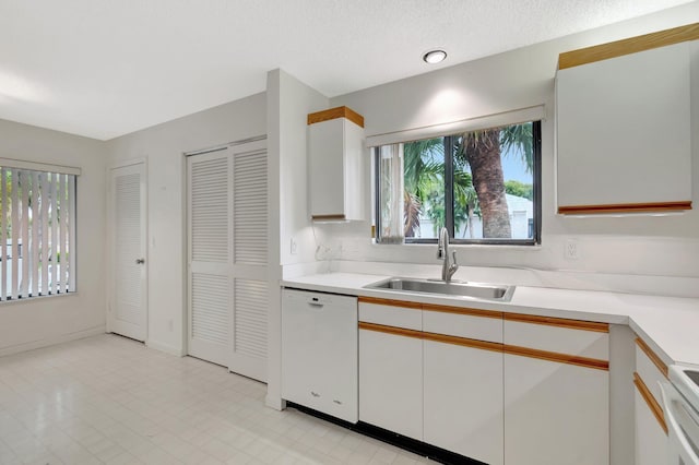 kitchen with a sink, white cabinets, light countertops, and white dishwasher