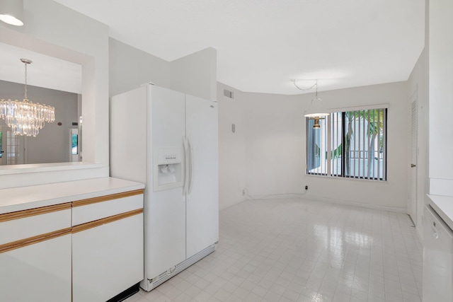 kitchen with visible vents, light countertops, an inviting chandelier, white fridge with ice dispenser, and white cabinets