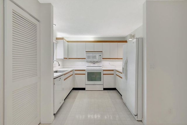 kitchen with white appliances, white cabinets, light countertops, and a sink