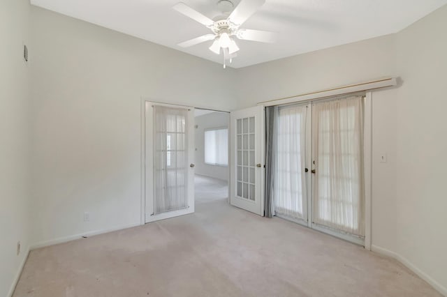 carpeted spare room with french doors, lofted ceiling, baseboards, and a ceiling fan