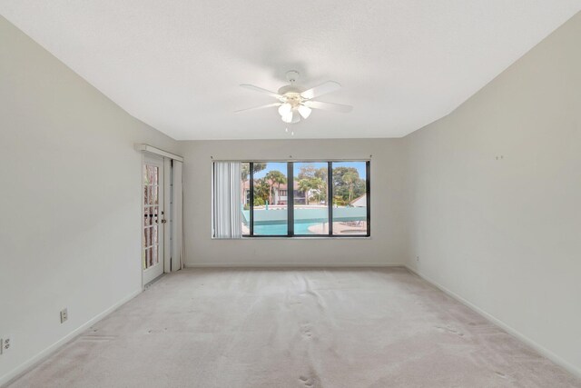 spare room with a ceiling fan, baseboards, and light carpet