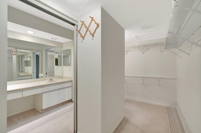 walk in closet featuring light colored carpet and a sink