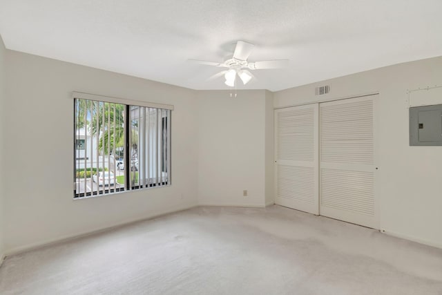 unfurnished bedroom with electric panel, visible vents, light carpet, and a closet