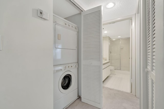 washroom featuring laundry area, light colored carpet, stacked washer / drying machine, and a textured ceiling