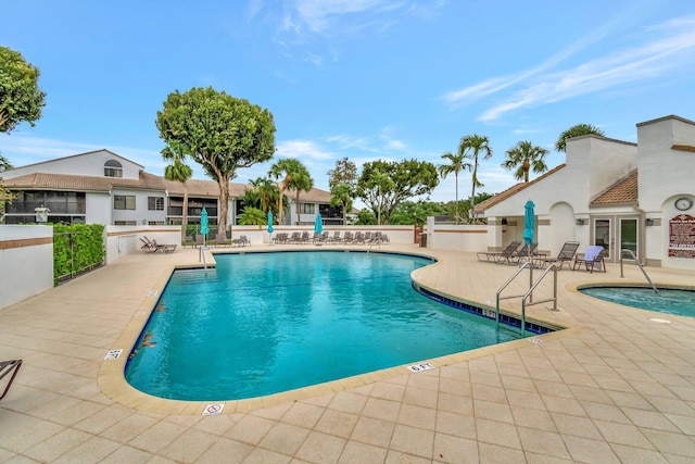 community pool with a patio area and fence