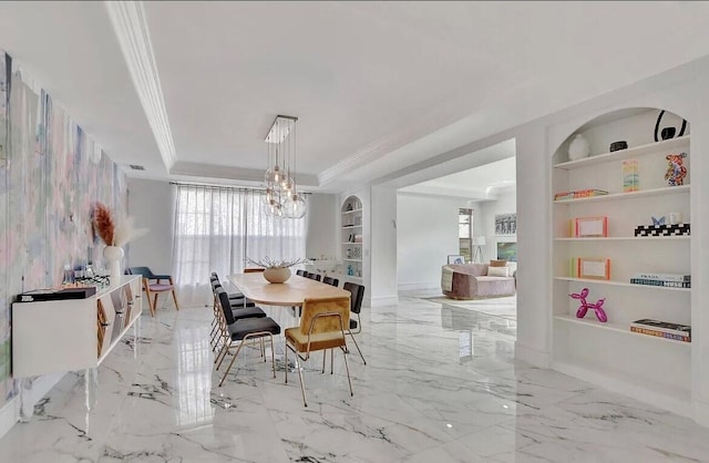 dining space featuring built in features, marble finish floor, ornamental molding, a raised ceiling, and an inviting chandelier