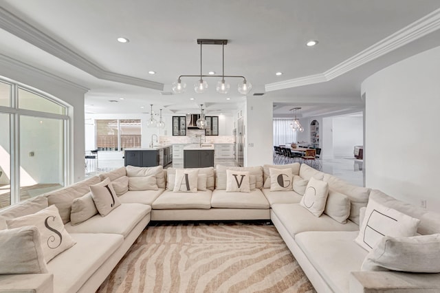 living area with recessed lighting, a raised ceiling, a healthy amount of sunlight, and crown molding