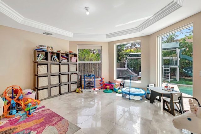 recreation room featuring a tray ceiling, a healthy amount of sunlight, crown molding, and visible vents