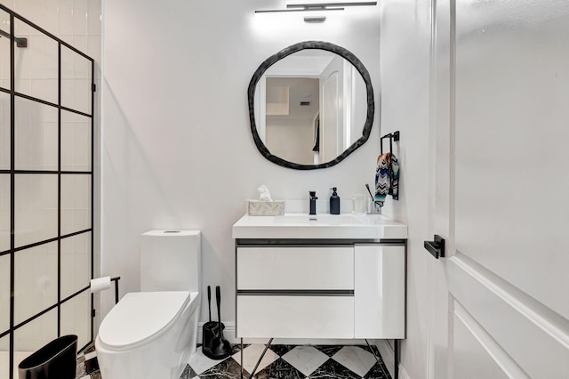 bathroom with vanity, a tile shower, and toilet