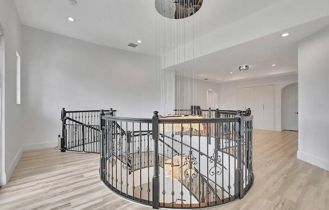 hall with baseboards, arched walkways, wood finished floors, and an upstairs landing