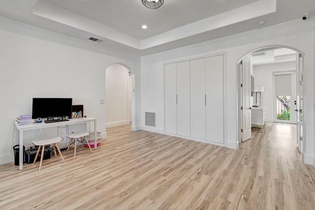 office featuring arched walkways, a tray ceiling, and visible vents