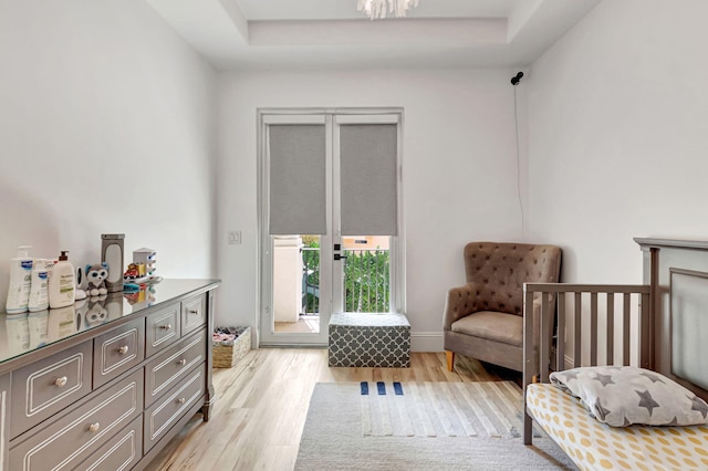 sitting room with a raised ceiling and light wood-style floors