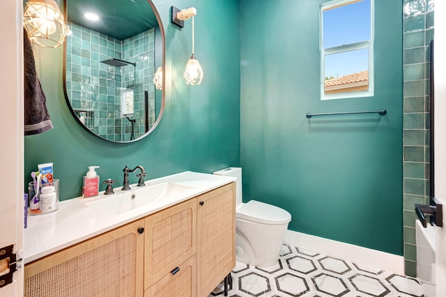 bathroom with toilet, tiled shower, and vanity