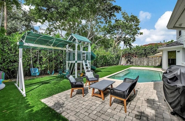 view of swimming pool featuring a patio, a yard, and a playground