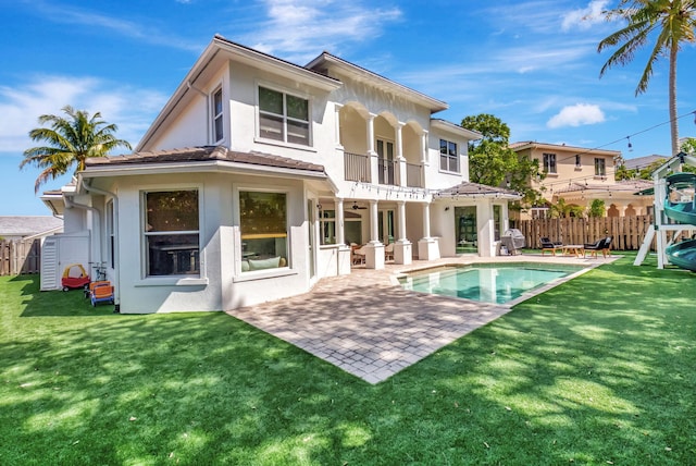 back of house featuring a yard, stucco siding, a patio area, fence, and a balcony