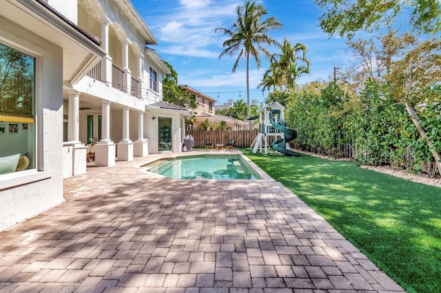 view of swimming pool with a patio area, a lawn, fence, and a playground