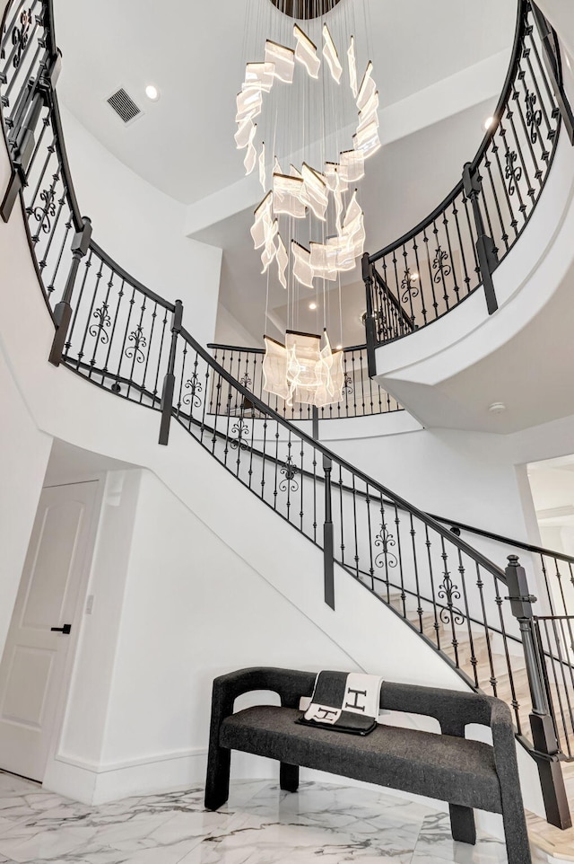 stairs featuring marble finish floor, a notable chandelier, recessed lighting, visible vents, and a high ceiling