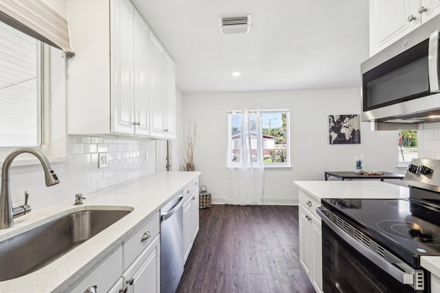 kitchen featuring visible vents, a sink, decorative backsplash, stainless steel appliances, and white cabinetry