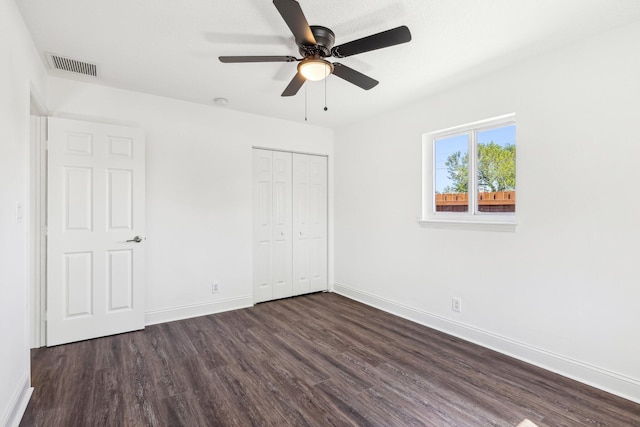 unfurnished bedroom with visible vents, ceiling fan, baseboards, dark wood finished floors, and a closet