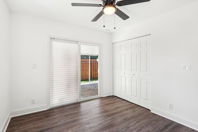 unfurnished bedroom featuring a closet, dark wood-type flooring, baseboards, and access to outside