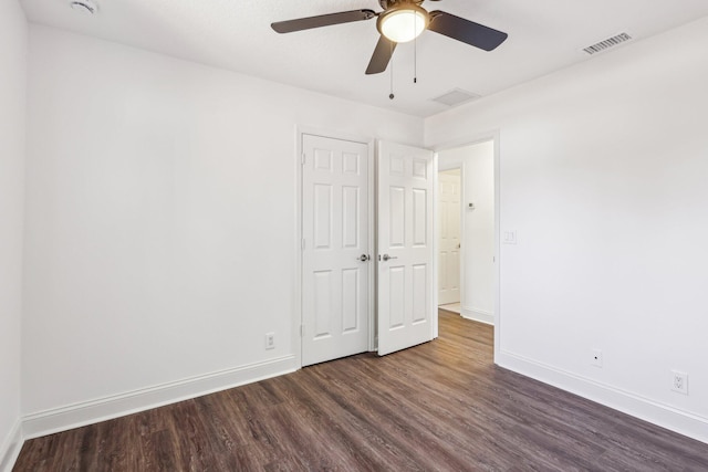 unfurnished bedroom featuring visible vents, baseboards, a ceiling fan, and dark wood-style flooring