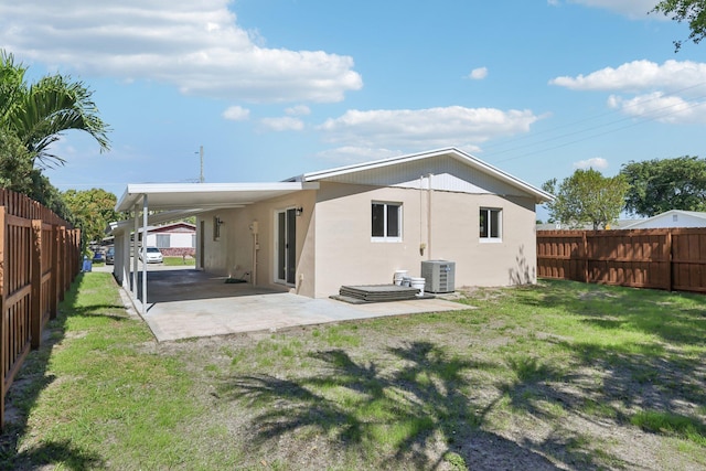 back of property featuring central AC, stucco siding, a yard, a fenced backyard, and a patio