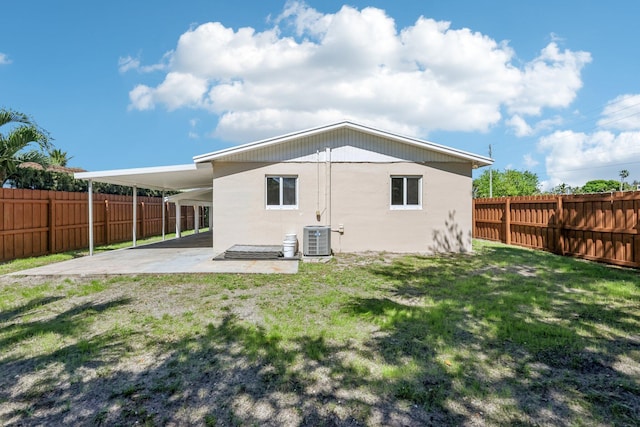 back of property featuring a yard, a carport, central AC unit, and a fenced backyard