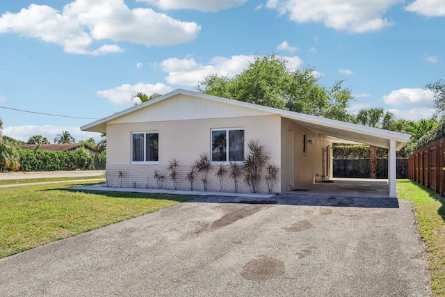 single story home with aphalt driveway, fence, a front lawn, a carport, and brick siding