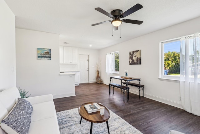 living area featuring visible vents, ceiling fan, baseboards, and dark wood-style flooring