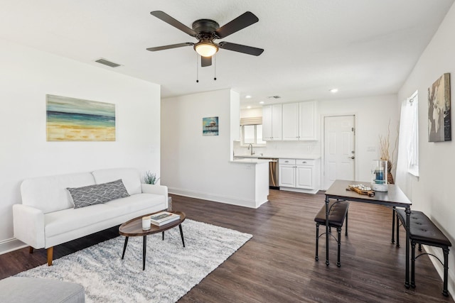 living area with dark wood-style floors, visible vents, a ceiling fan, and baseboards