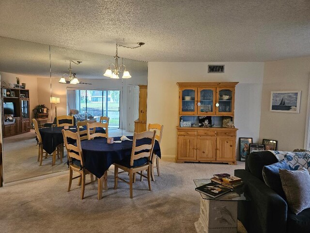 dining room featuring light carpet, a textured ceiling, visible vents, and a notable chandelier