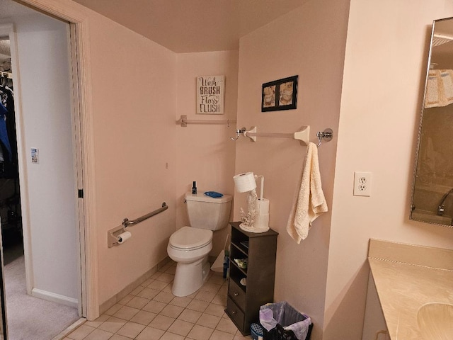 bathroom featuring a spacious closet, toilet, vanity, baseboards, and tile patterned floors