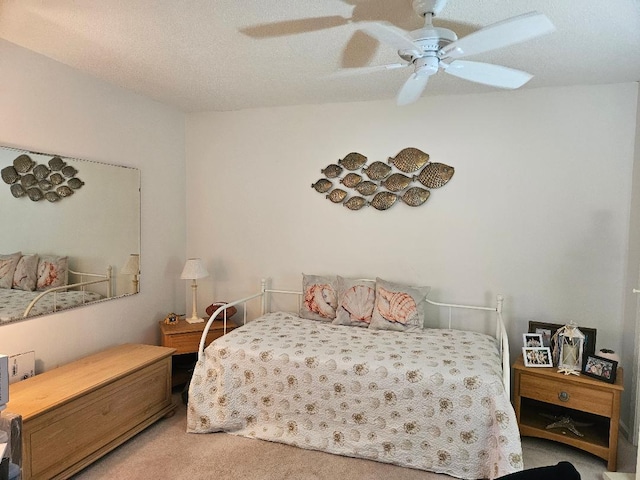 carpeted bedroom featuring ceiling fan and a textured ceiling