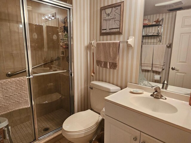 bathroom with a stall shower, vanity, toilet, and wallpapered walls