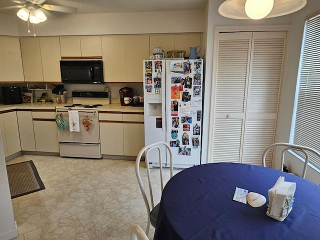 kitchen featuring a ceiling fan, white appliances, light countertops, and light floors