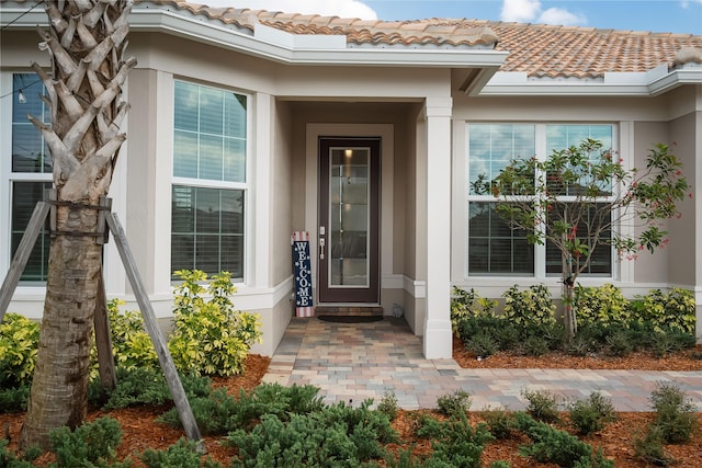 property entrance with a tile roof and stucco siding