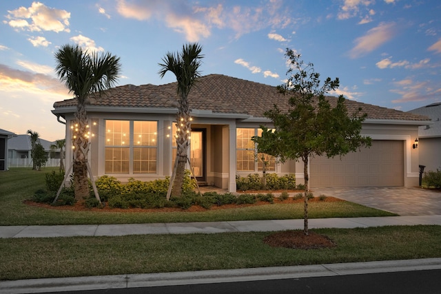 ranch-style home with a tile roof, an attached garage, driveway, and stucco siding