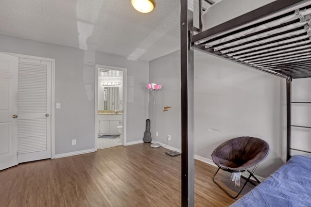 154 Weybridge Cir Unit C, Royal Palm Beach, FL 33411 - unfurnished bedroom featuring ensuite bath, a textured ceiling, baseboards, and wood finished floors
