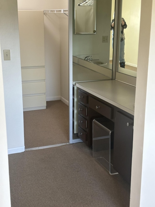 unfurnished office with carpet floors, a sink, and baseboards