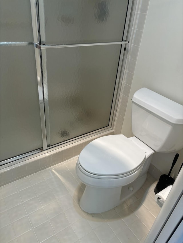 bathroom featuring a stall shower, toilet, and tile patterned floors