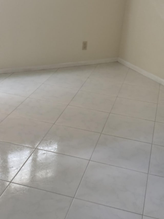 empty room featuring light tile patterned flooring and baseboards